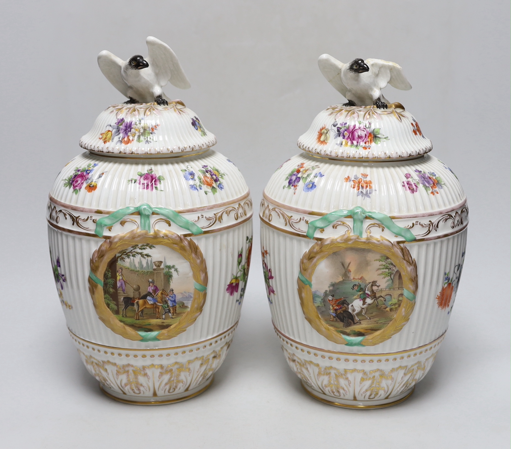 Two Dresden porcelain vases with bird decoration finials, and central horse scenes display, 30cm tall